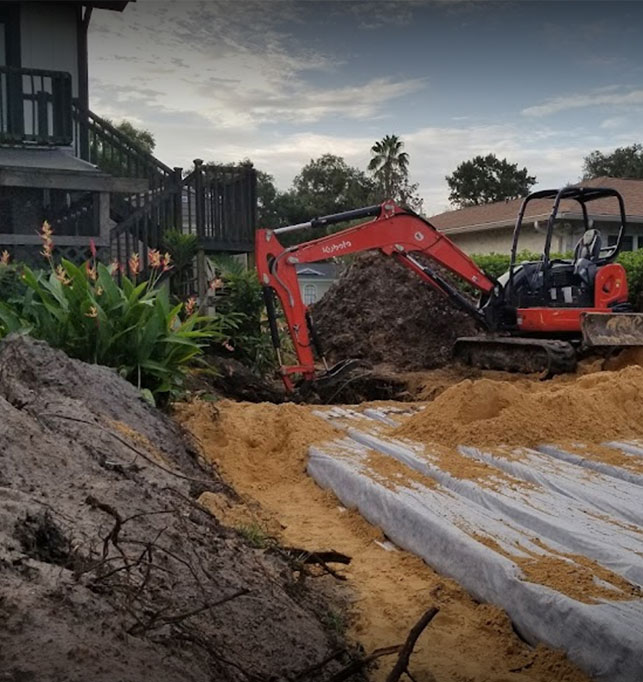 An image of ACE Septic & Waste's excavator machine digging in a backyard to put in a septic system.